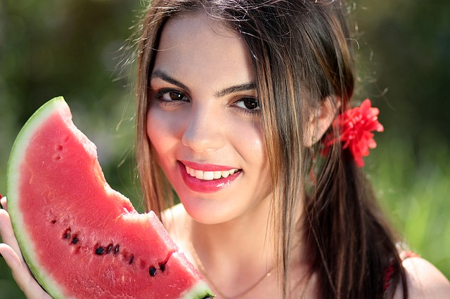Mladá usmiata žena s červeným melónom v ruke